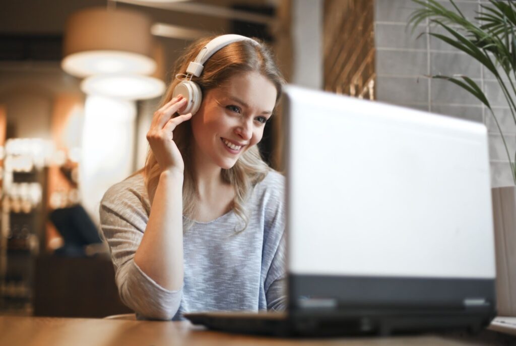 a smiling young woman using a laptop in a cafe